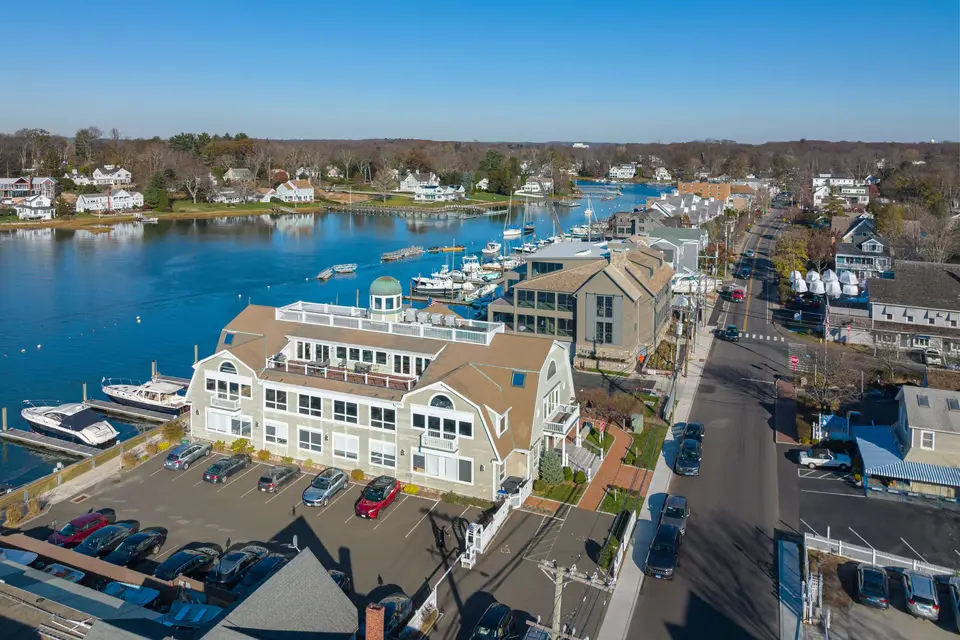 Aerial view of Norwalk, Connecticut showing a waterfront marina, residential neighborhood, and downtown streets along the harbor on a clear day.