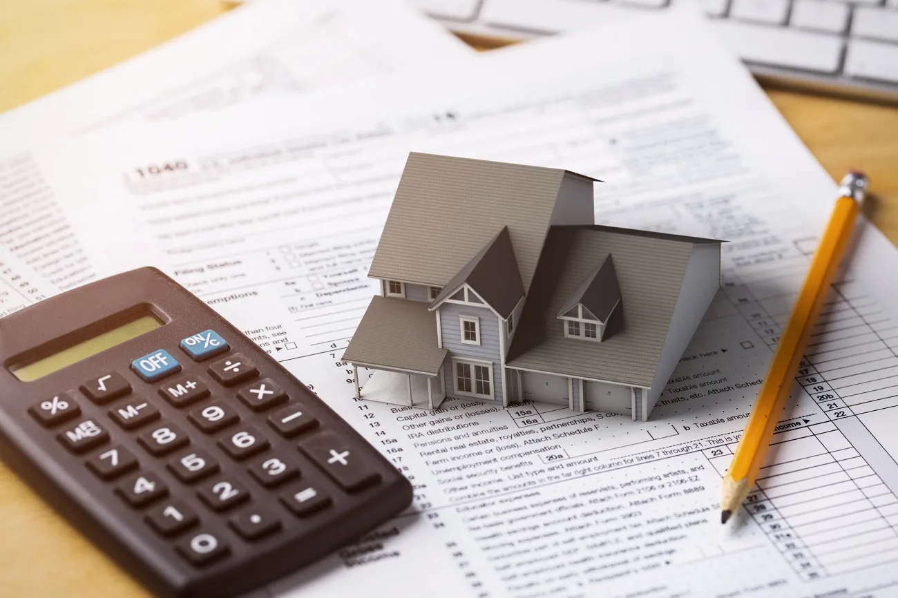 Calculator and house model on tax forms representing property taxes.