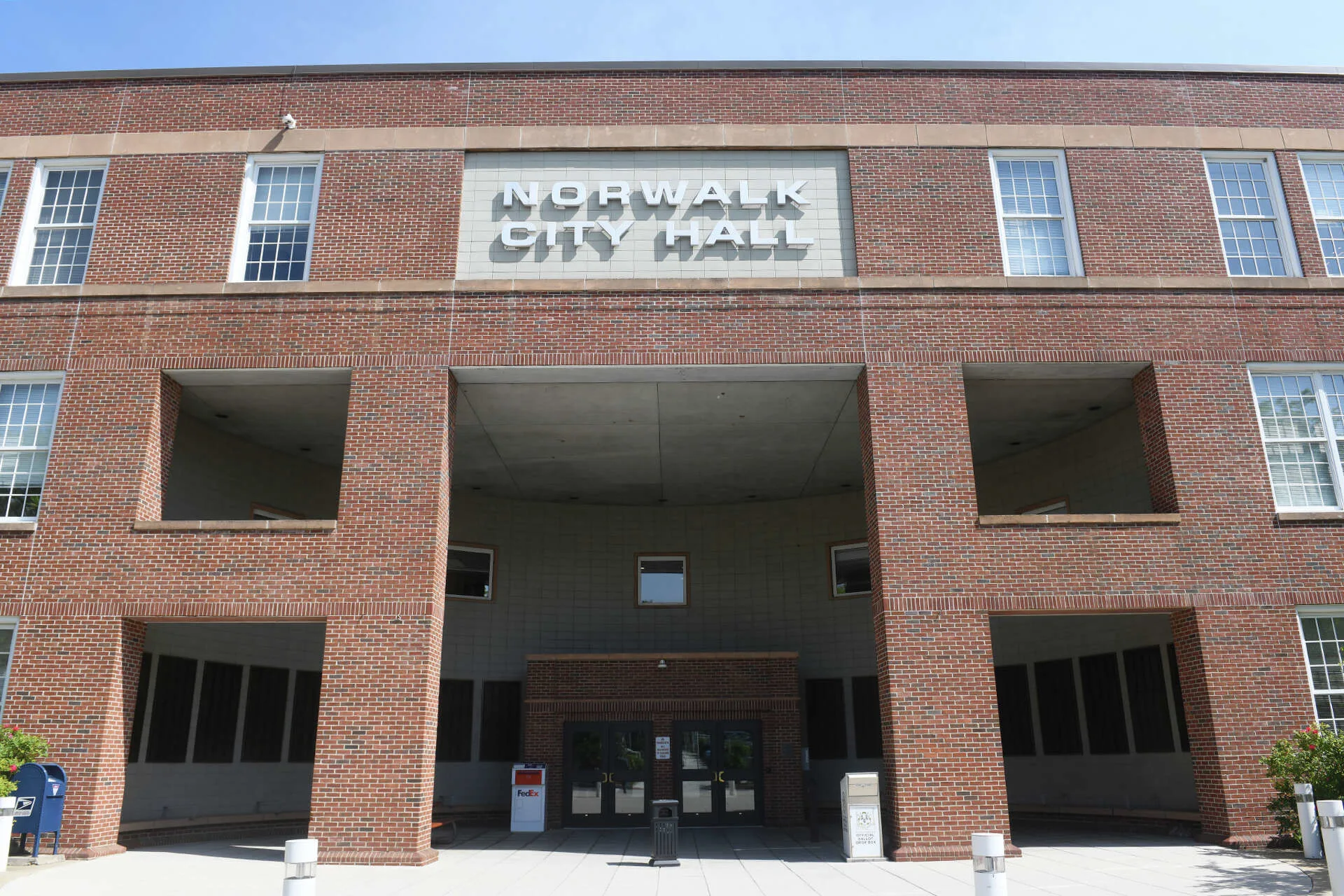 Front view of Norwalk City Hall, a red brick municipal building with a central entrance