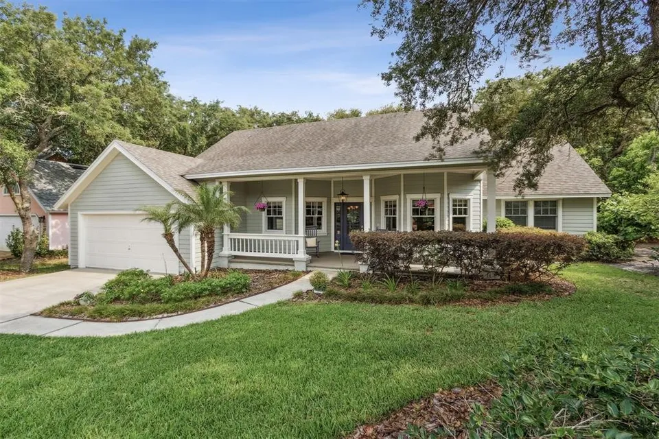 Front view of a single-story suburban house with a garage, porch, and landscaped lawn.