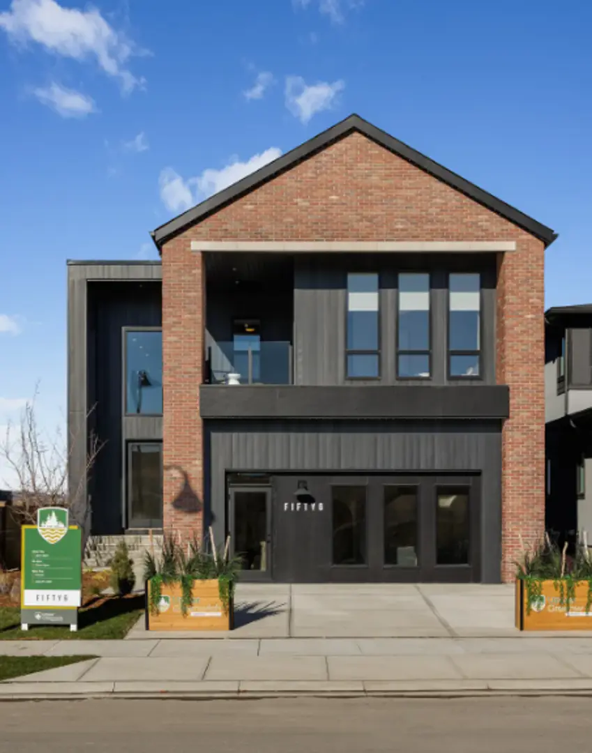 Greenwich real estate contemporary red brick home with dark metal cladding, upper balcony, wide garage entry, and planter boxes