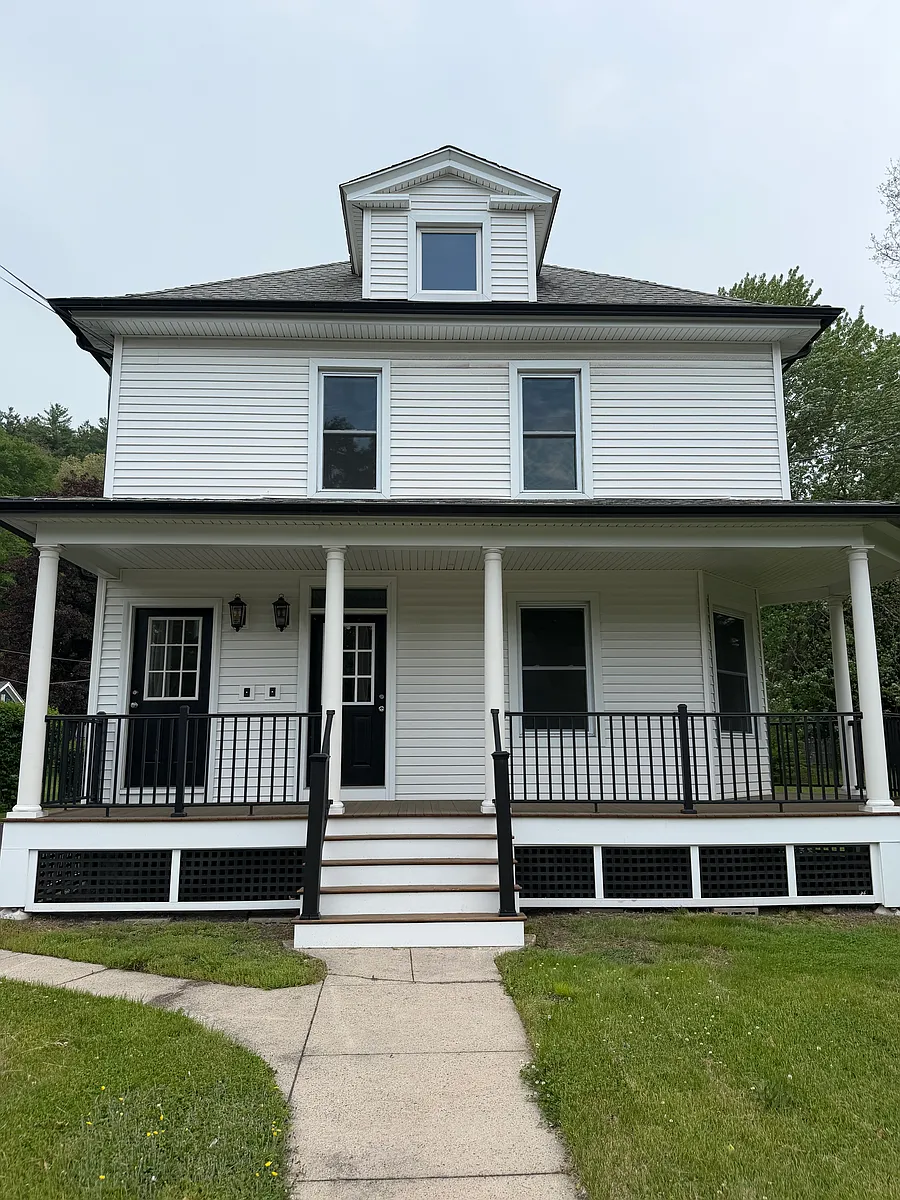 Hamden real estate white two-story colonial home with wraparound porch, black columns railings, and front gabled dormer