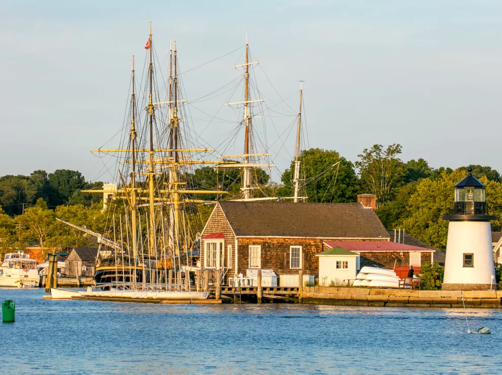 Historic harbor with tall ships and lighthouse.