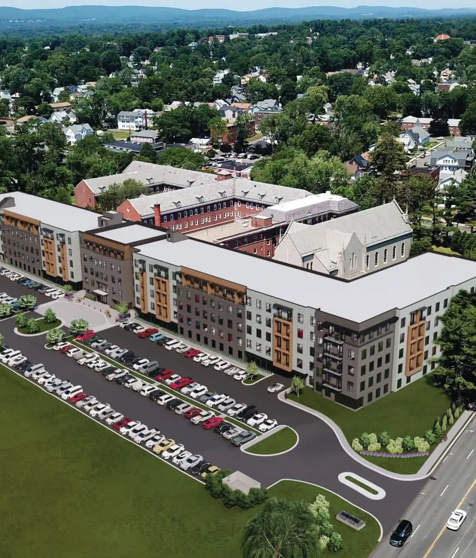 West Hartford real estate aerial view of modern mixed-use development with wood accents, historic chapel, and large parking lot