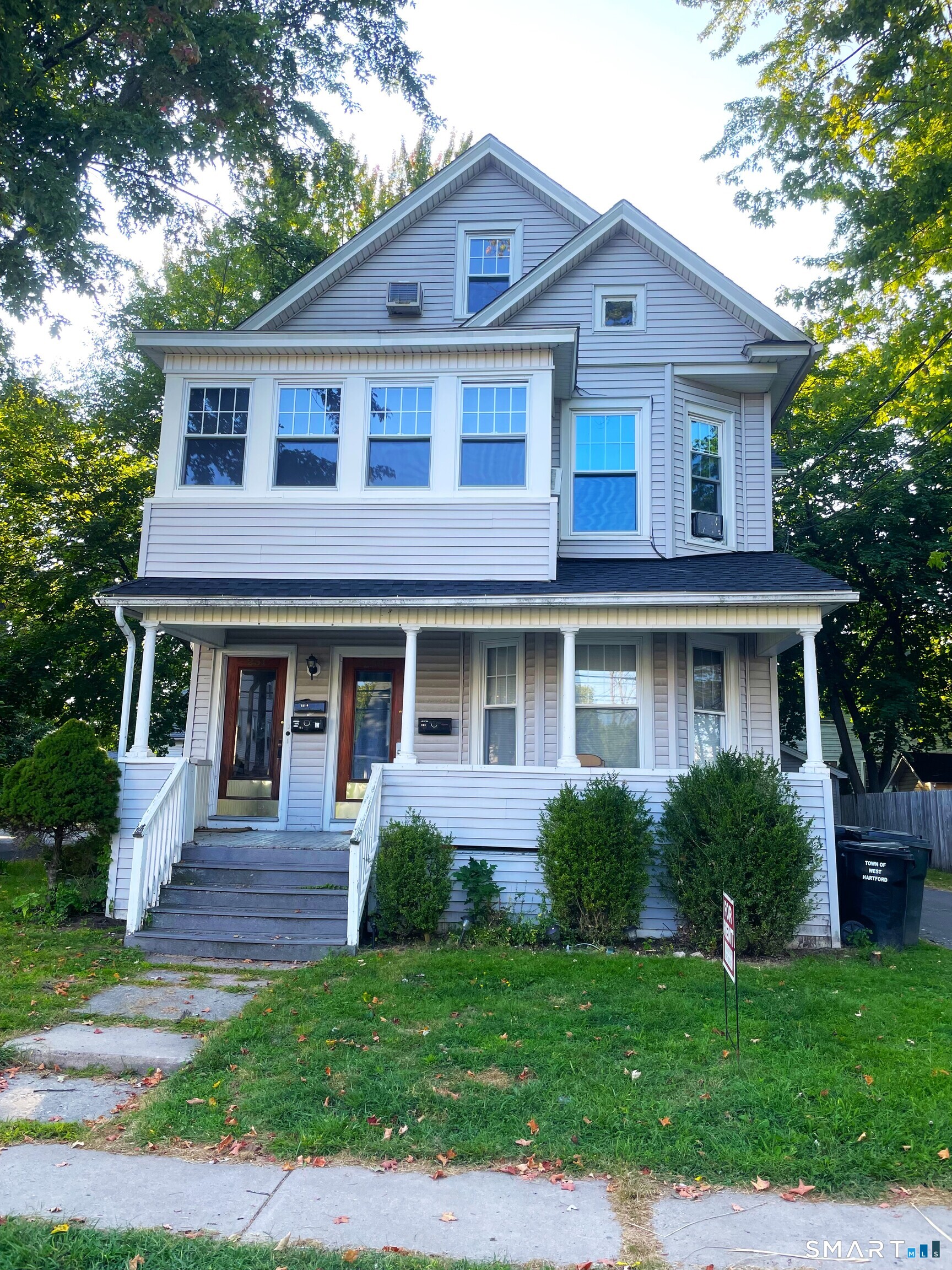 West Hartford real estate gray three-story Victorian home with covered porch, red door, bay windows, and green front lawn
